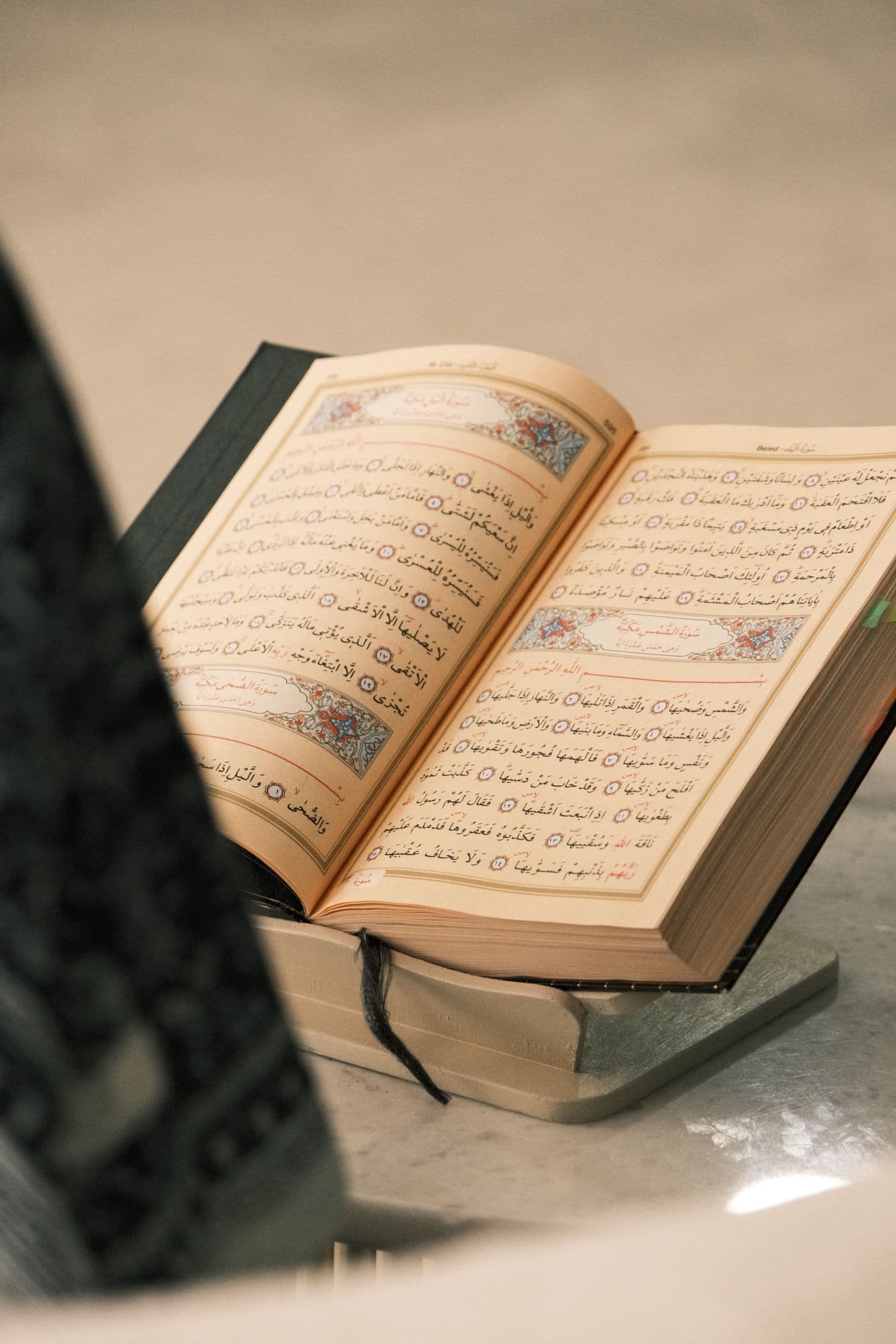 An open Qur'an resting on a wooden stand in soft light