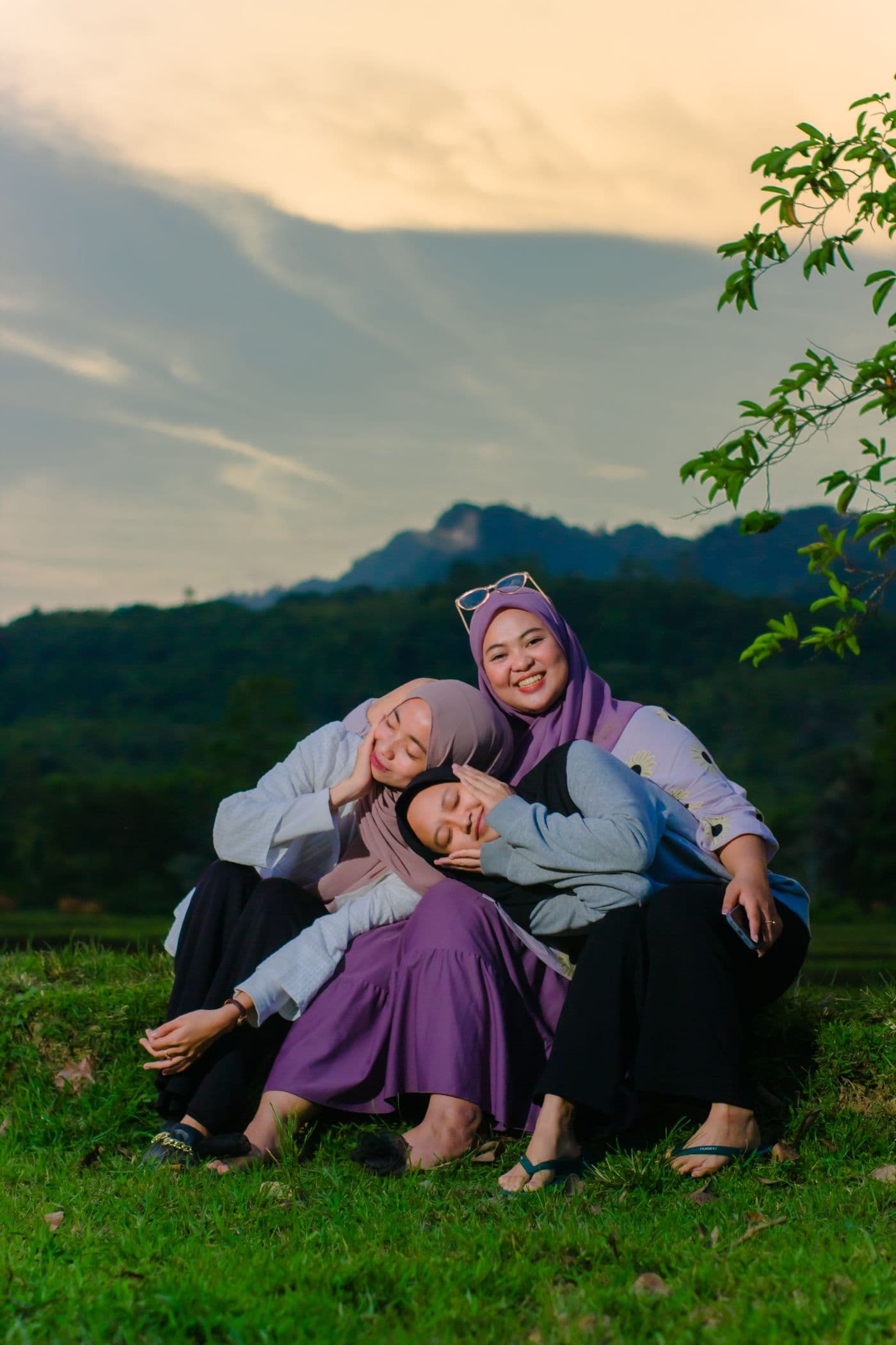 Friends in hijab sitting together at sunset